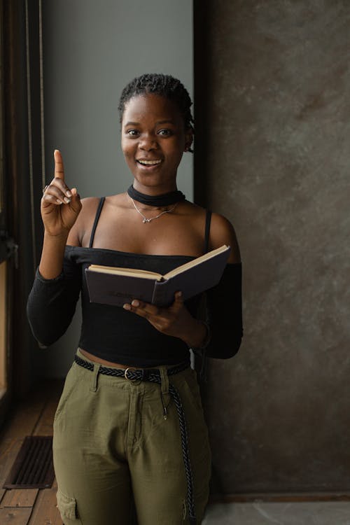 Free Black woman standing in room and reading book Stock Photo
