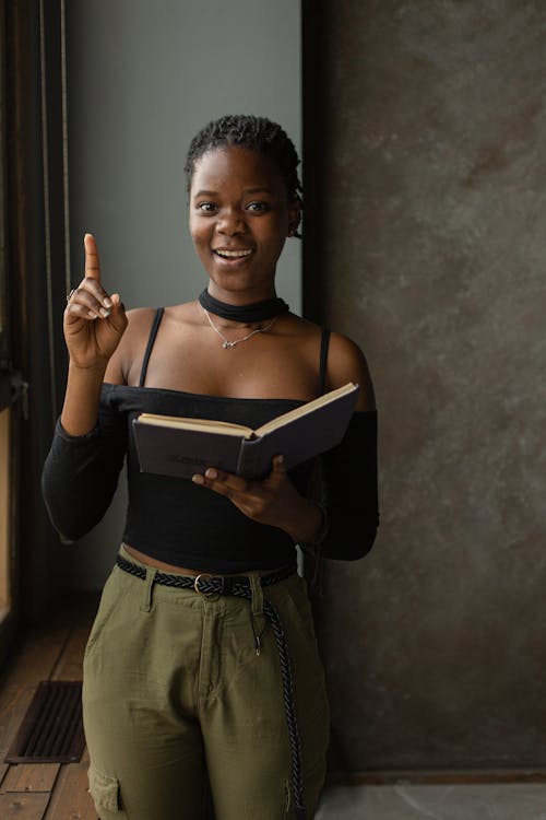 Black woman standing in room and reading book