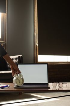 A serene office setting with a laptop, alarm clock, and eyeglasses on a modern desk.