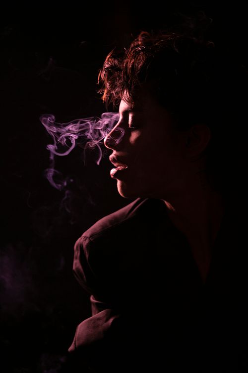 Free Silhouette of a person exhaling smoke in a dramatic, moody setting. Stock Photo