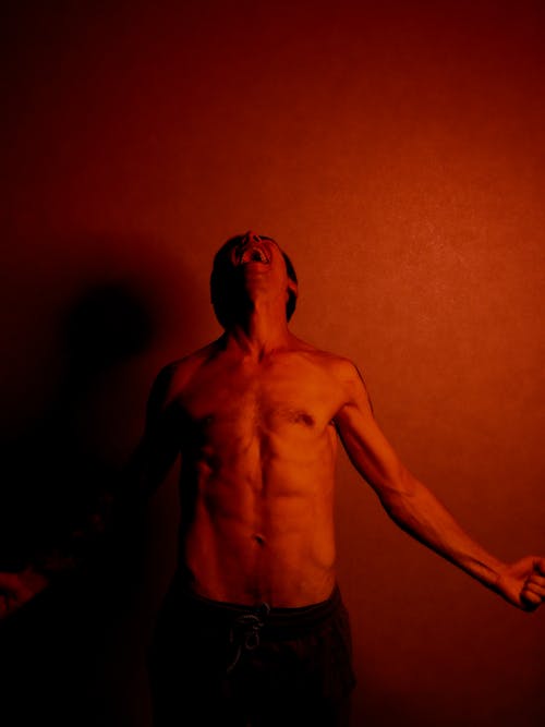 Shirtless Man Looking up in Red Illumination