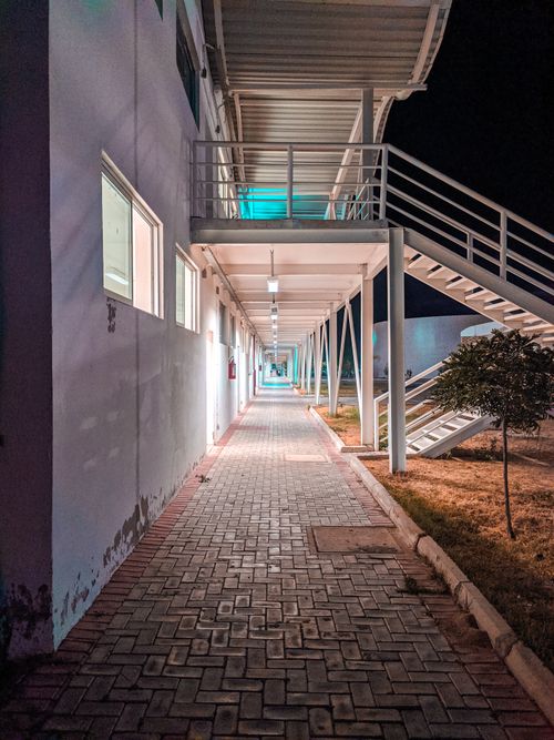 Free A modern building exterior with an illuminated walkway and stairs at night. Stock Photo