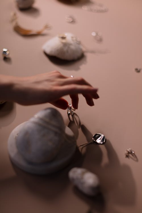 Close-up of Woman Putting a Piece of Jewelry next to a Pebble 