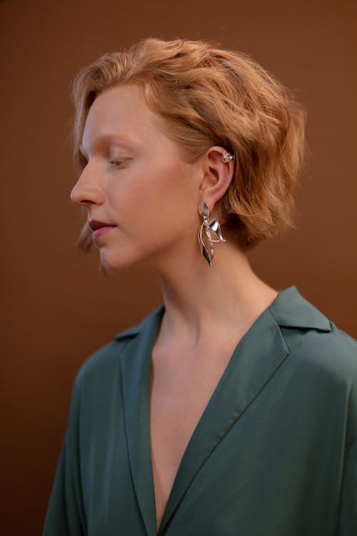 Side View of a Woman Wearing Her Silver Earring on Brown Background