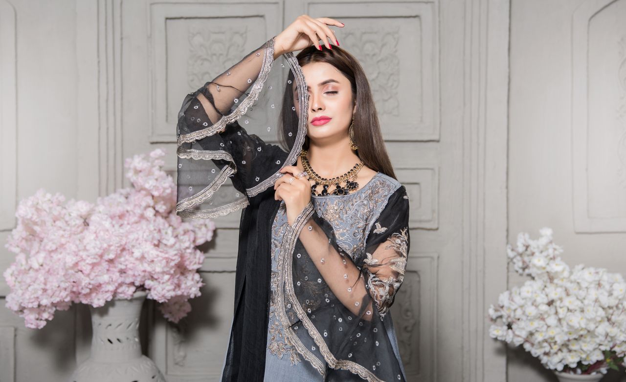 portrait of an elegant woman in a black embroidered dress posing with