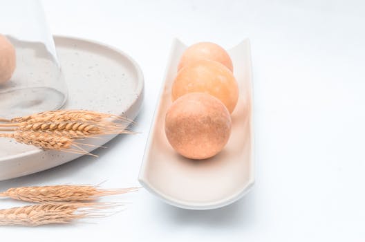 Minimalist setup of ceramic plates and fresh bread rolls on a bright background.