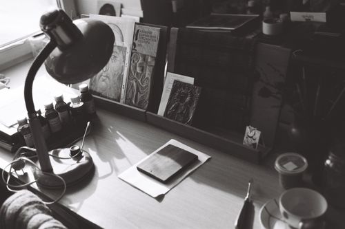 Free A monochrome desk setup featuring vintage art materials and a classic lamp in an artistic workspace. Stock Photo