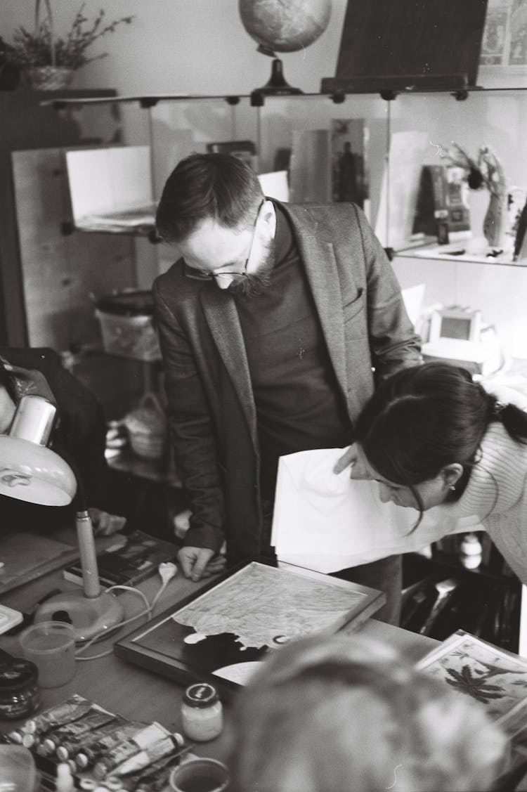 Black And White Photography Of Experts In A Studio Looking At Painting