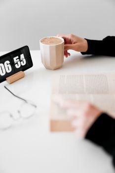 A serene morning setup with a coffee mug, book, and digital clock, evoking relaxation.