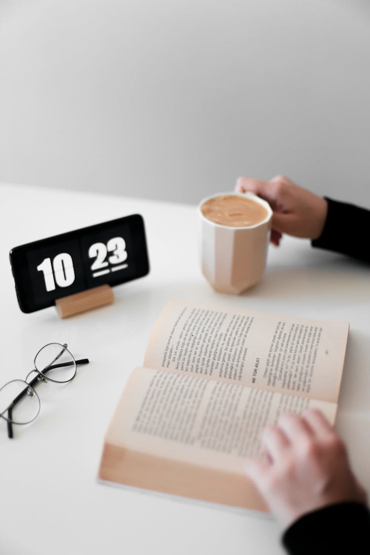 Hands And Book And Clock On Table