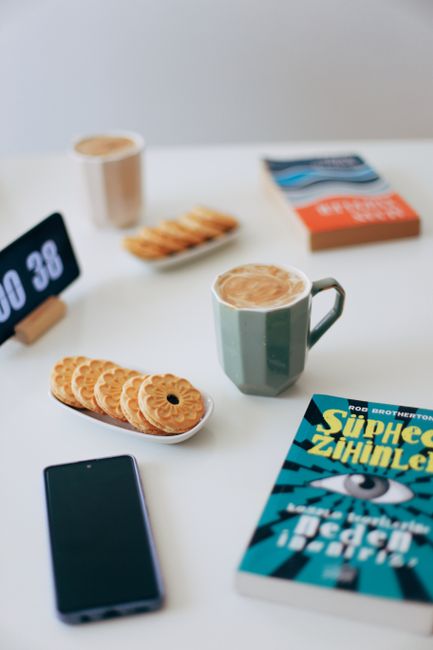 A relaxing setup with coffee, books, and biscuits on a table, perfect for a serene break.