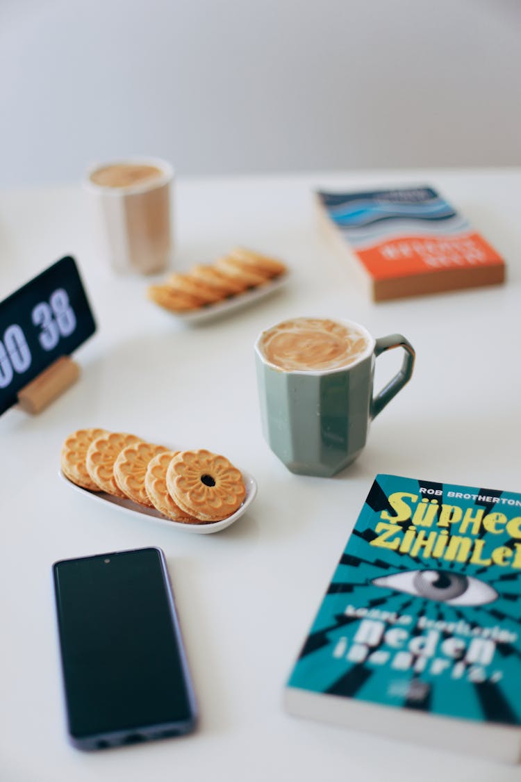 Cellphone, Cookies And Coffee Cup Near Book