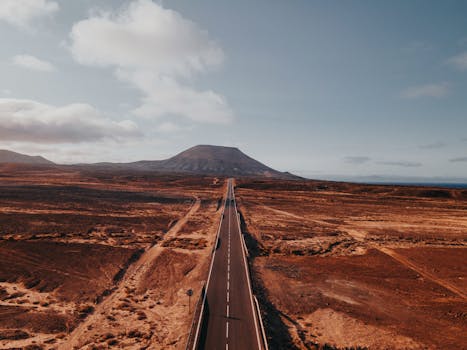A captivating aerial view of a road stretching through barren volcanic landscapes in Spain.
