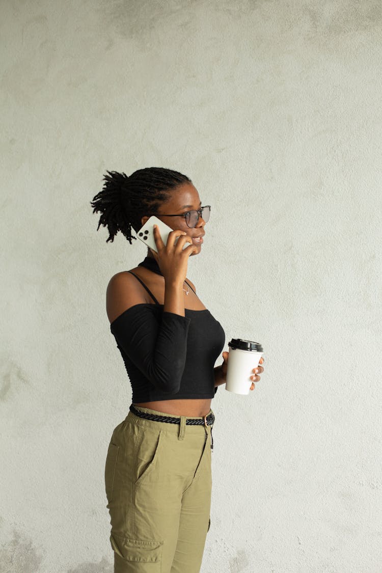 Young Black Woman Drinking Takeaway Coffee And Talking On Phone