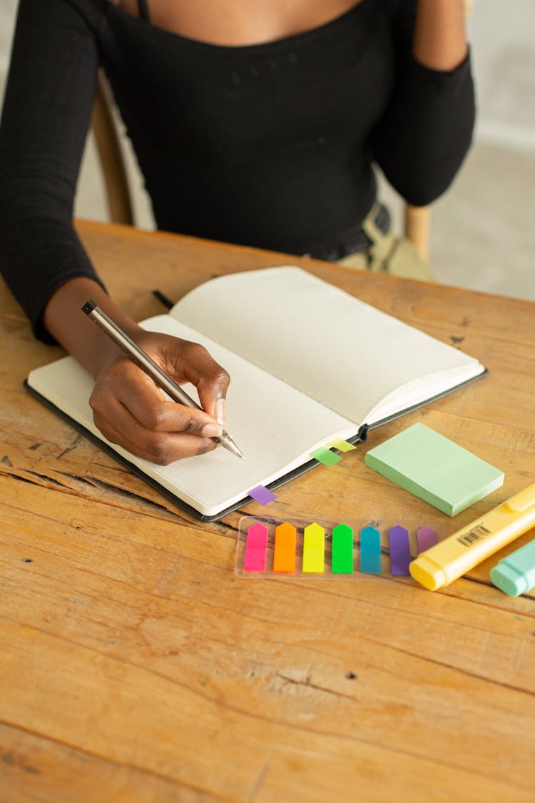 Crop Anonymous Black Woman Writing In Notebook