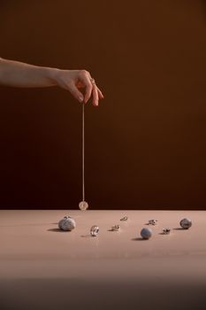 Delicate hand arranging a necklace amidst scattered gems on a reflective table.