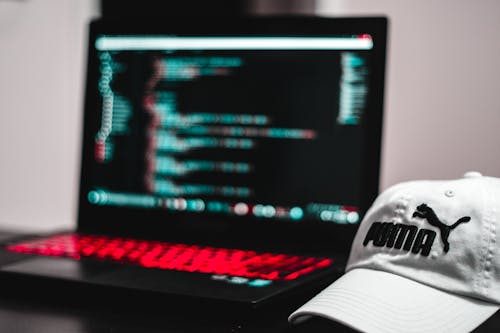 Black and Red Laptop Computer Beside White Puma Curve Brim Cap