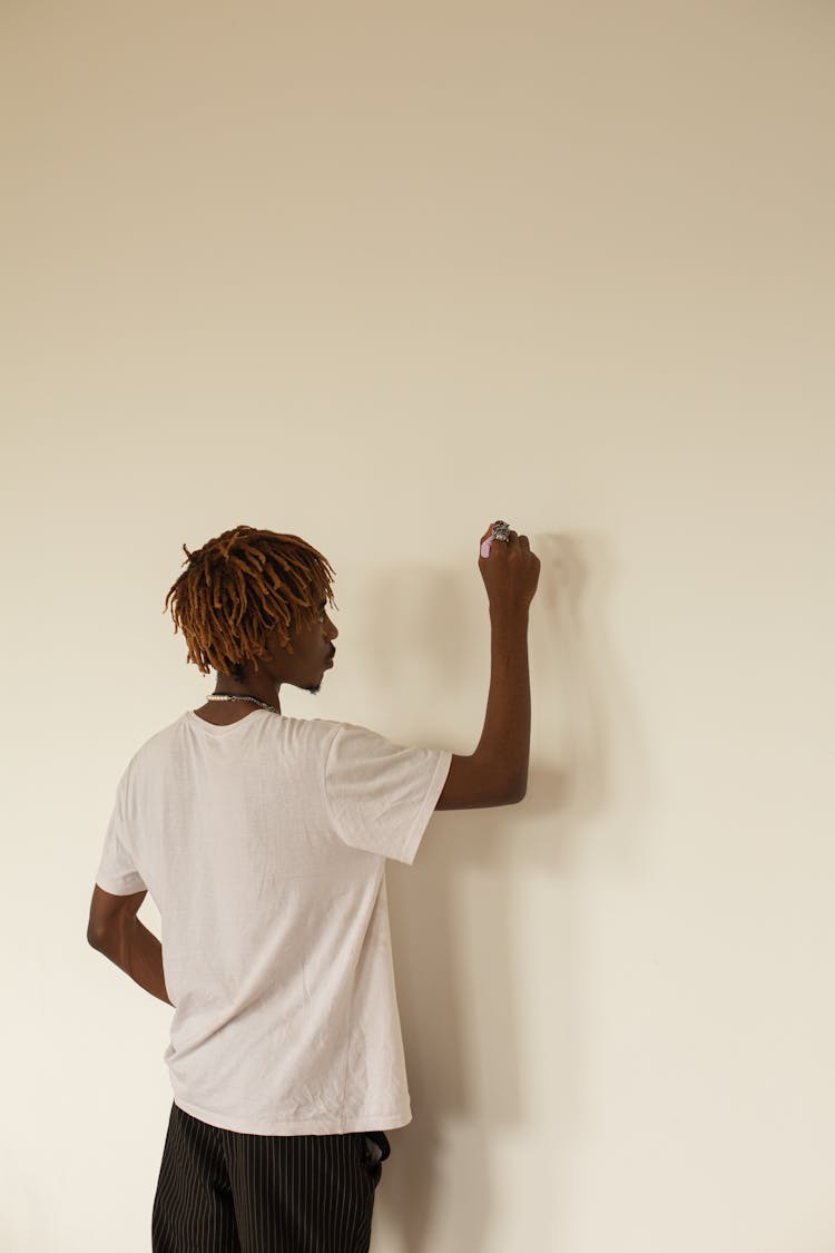 Young Black Man With Dreadlocks Writing On Wall