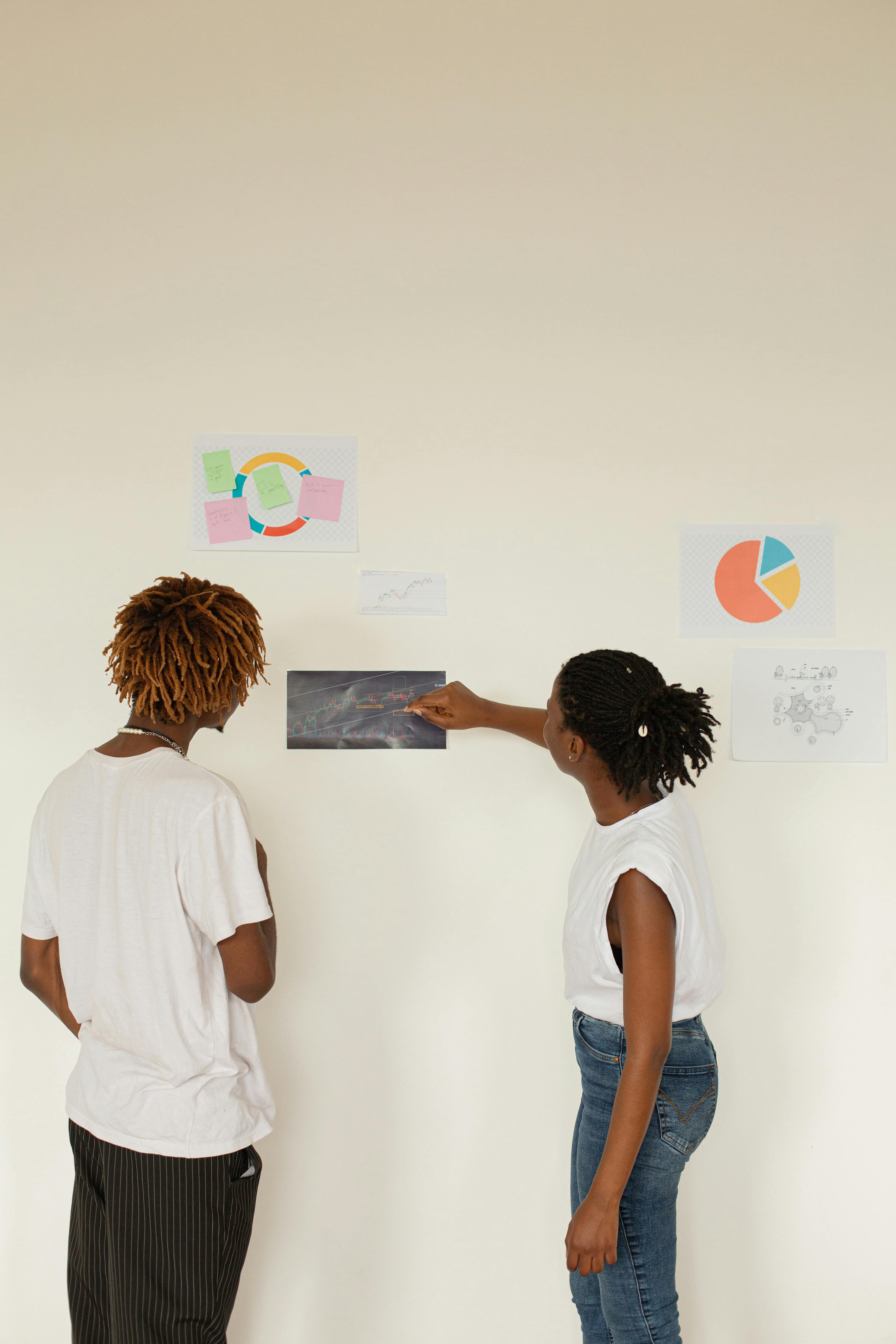 Woman and Man Pinning Images on Wall · Free Stock Photo