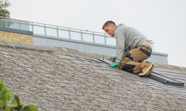 Roof Leak Repair โ Construction worker installing shingles on a rooftop. Outdoor building maintenance.