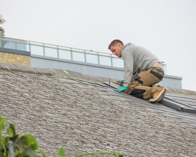 Shingle roof being installed Construction worker nailing new shingles onto a rooftop