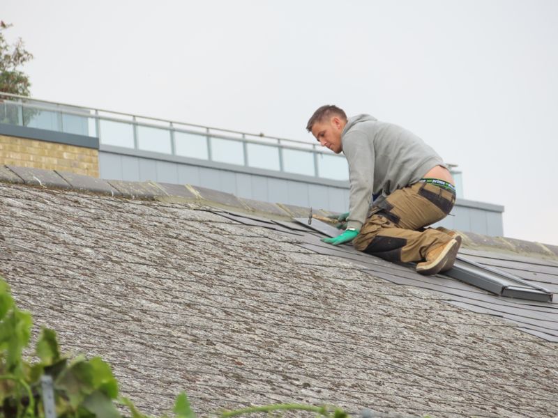 Roofer installing shingles on residential roof