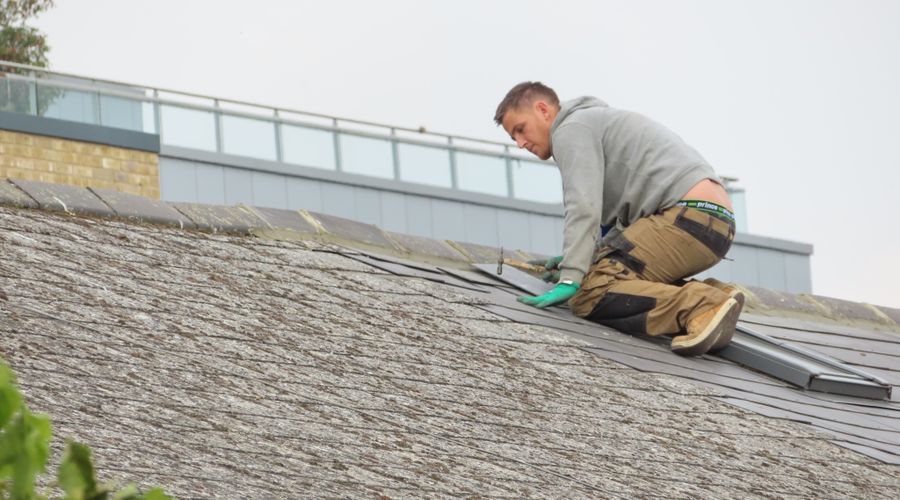 Close-up of damaged shingles being replaced by a roofer
