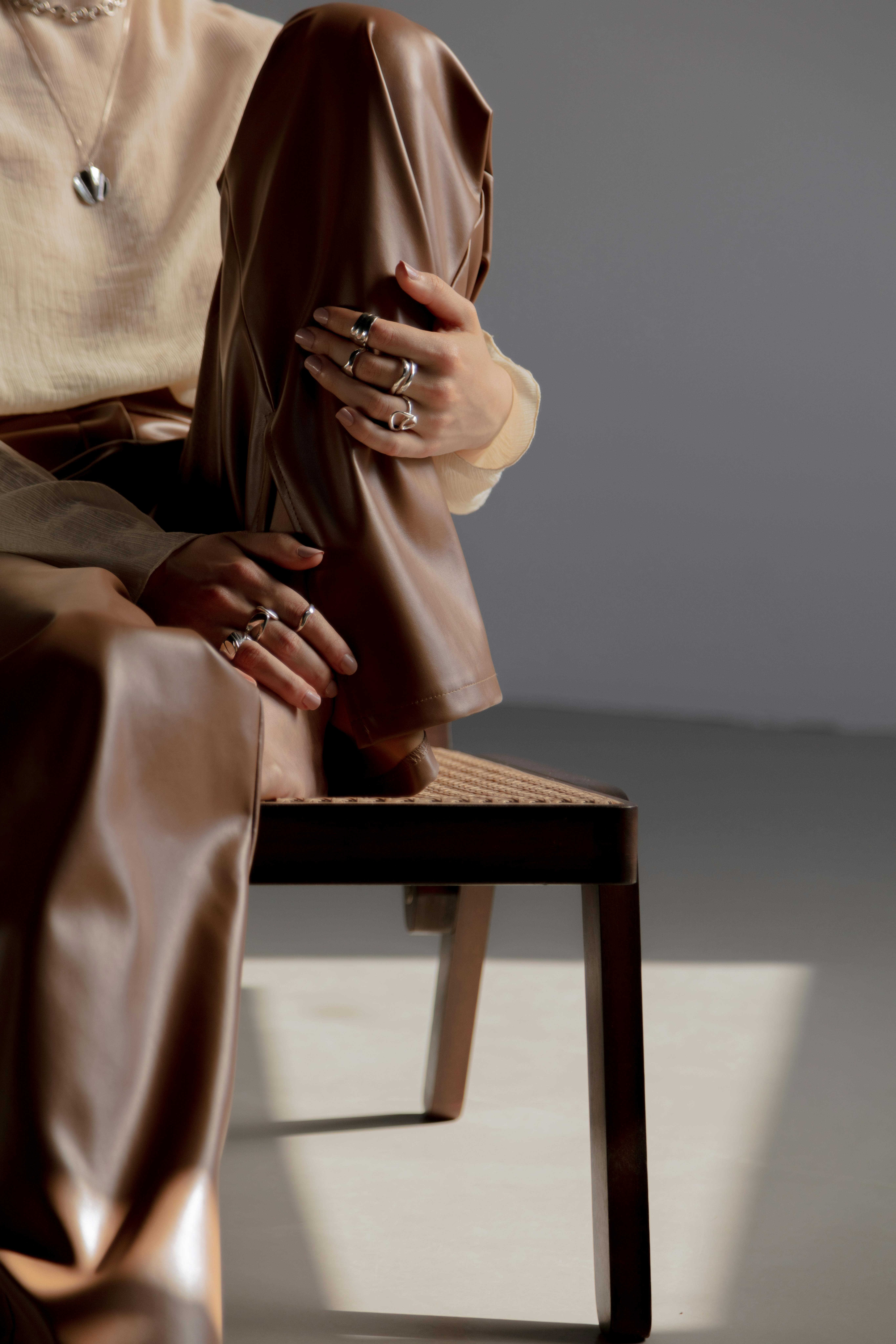 person sitting on brown wooden chair wearing silver rings