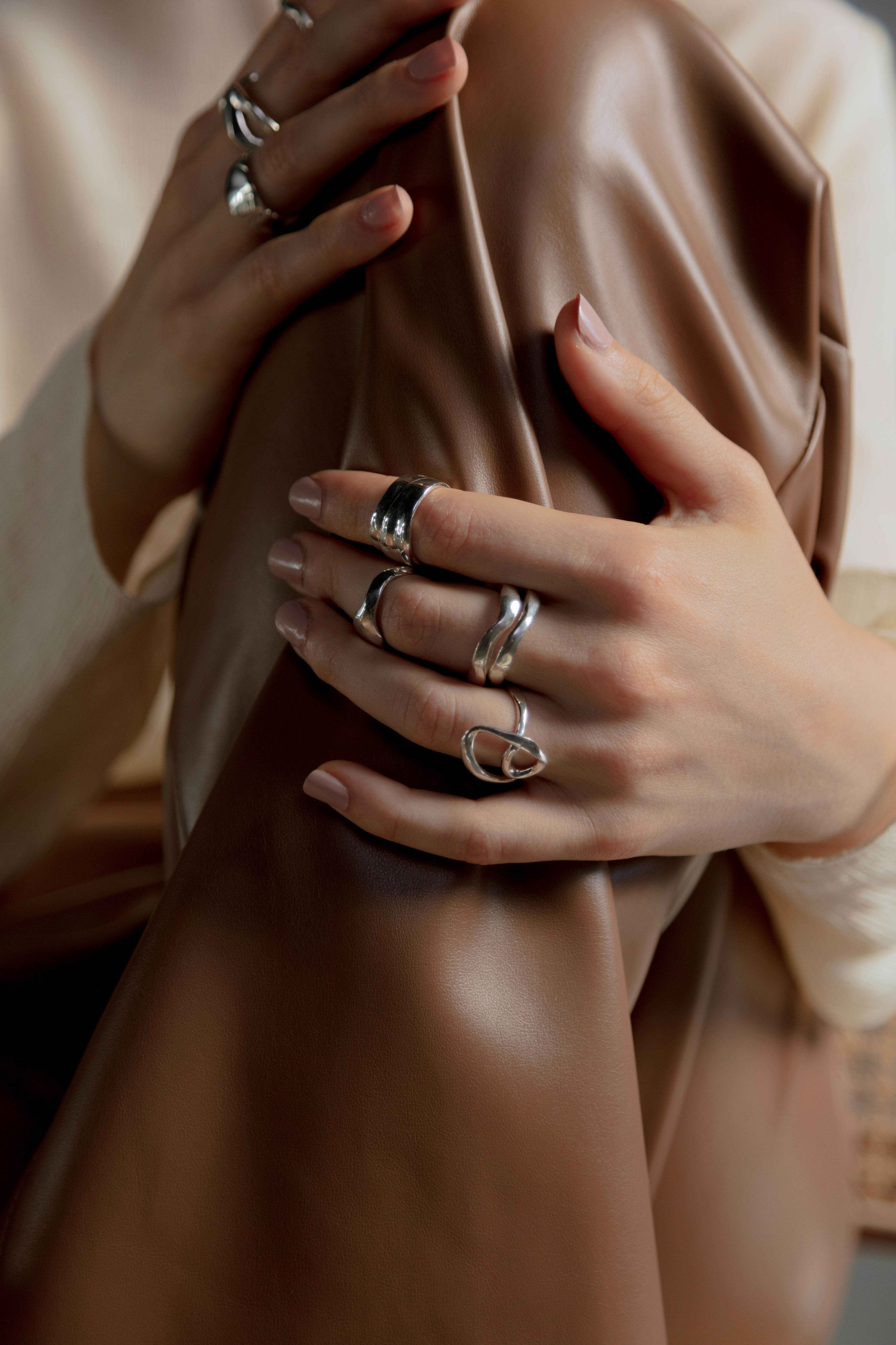 person wearing silver rings holding leather garment
