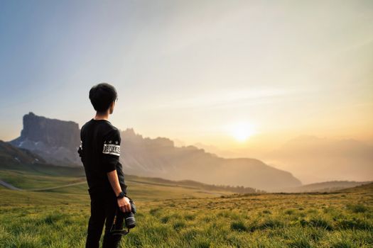 A photographer holding a camera, gazing at a stunning mountain sunset, capturing the essence of nature.