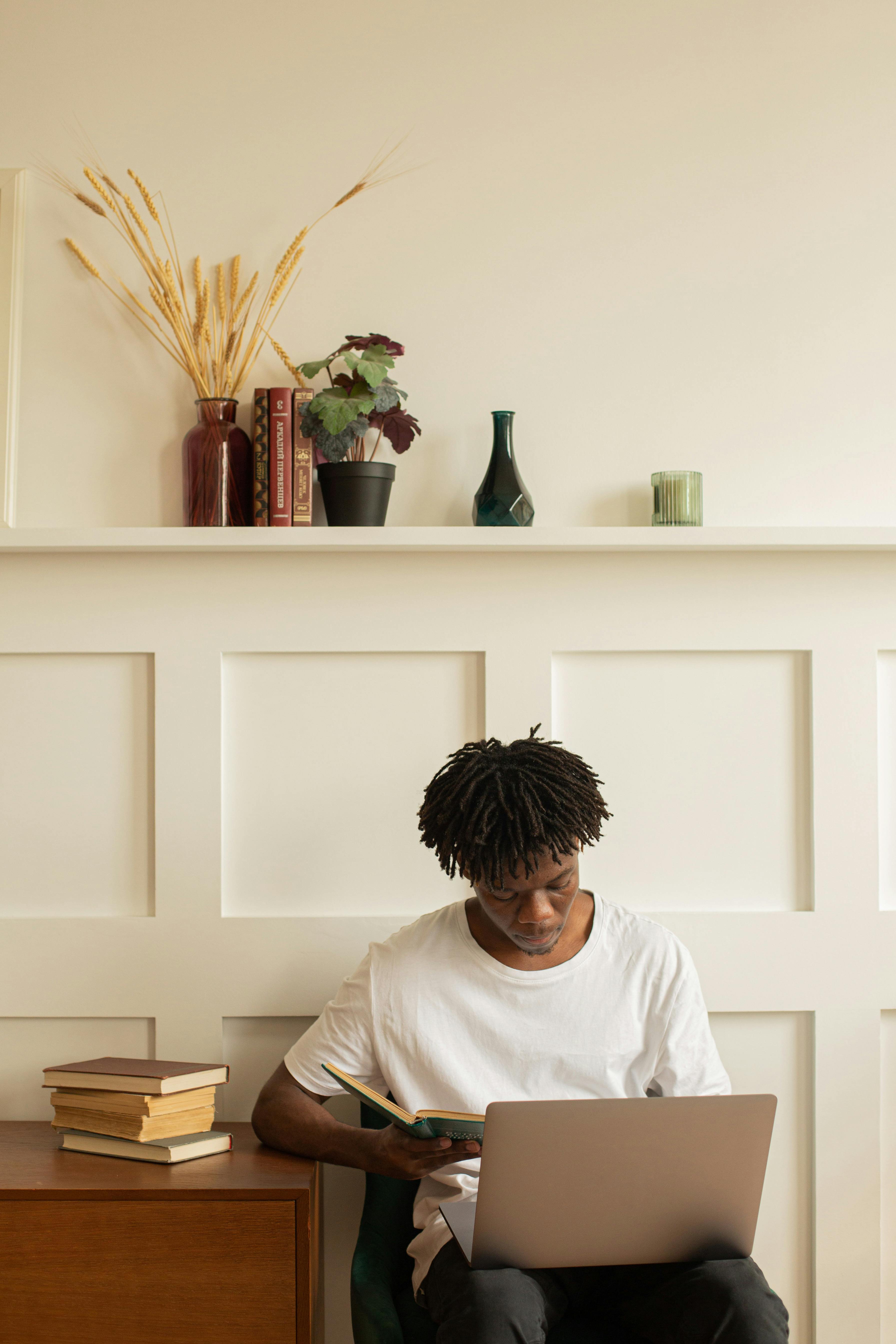 African American man studying at home with a laptop and books. Cozy interior setting.