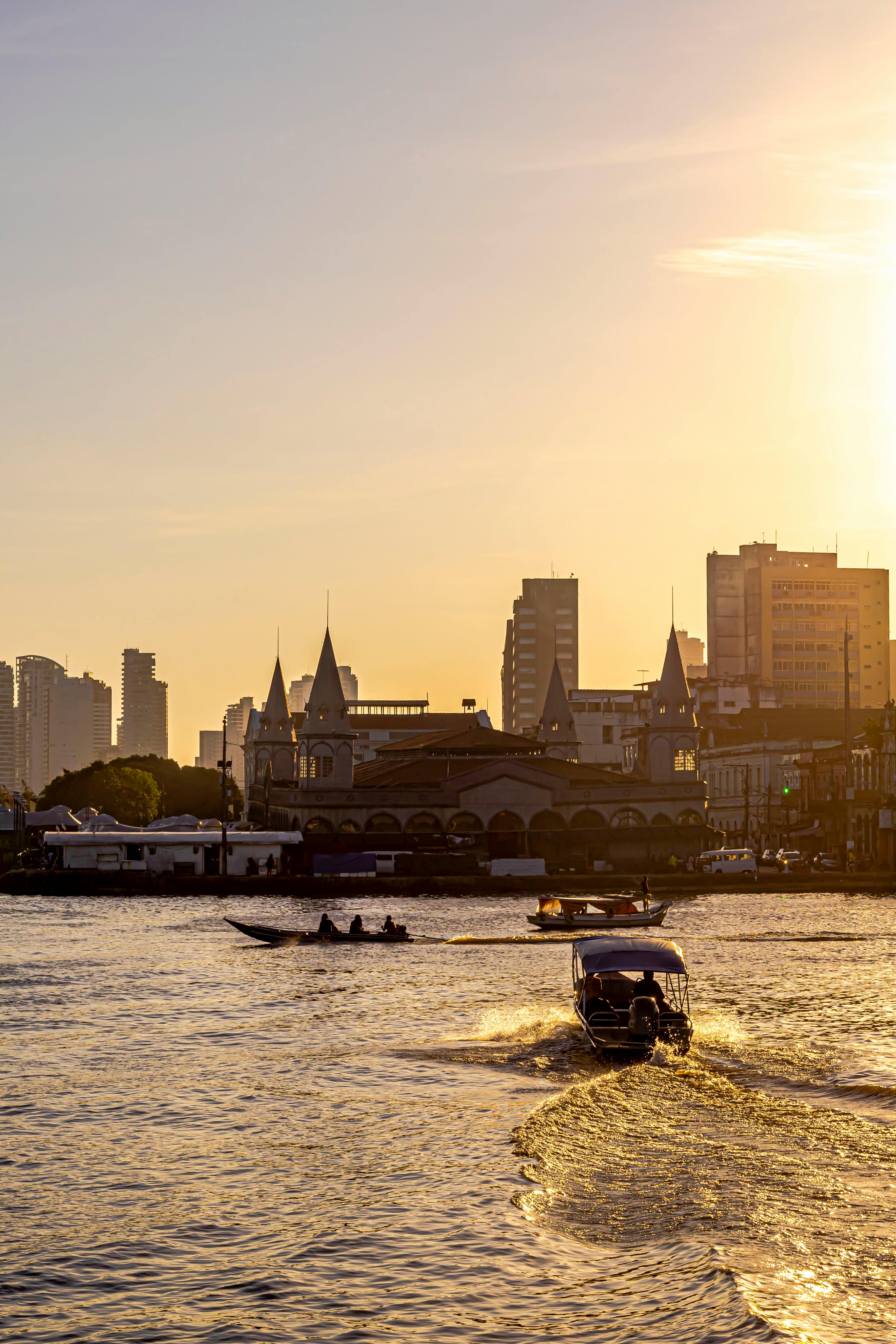 Boats along the Belém waterfront at dusk with historic city buildings and the river in view.