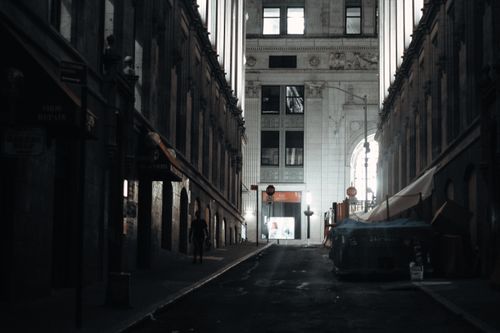 Free Moody city street scene with illuminated architectural details in a quiet alleyway at night. Stock Photo