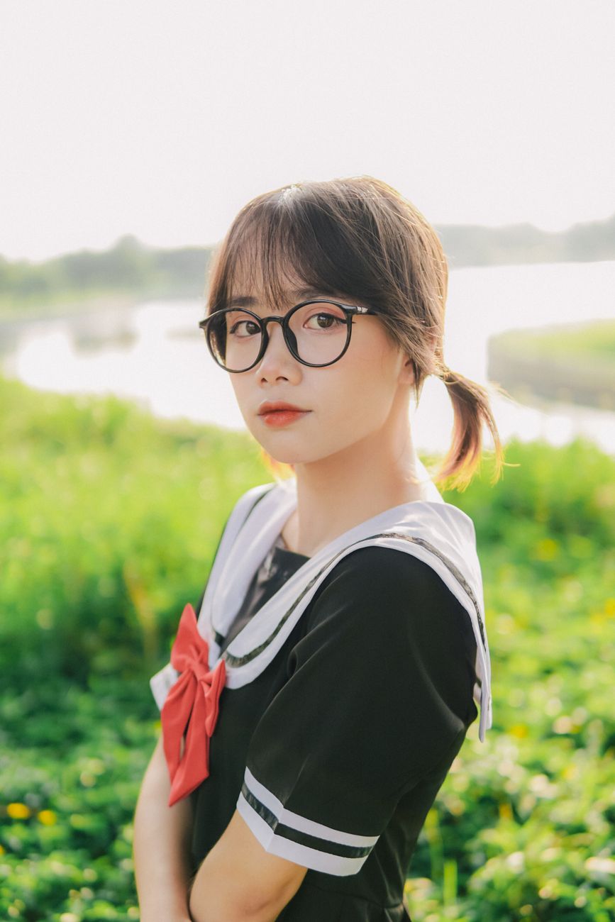 Beautiful young woman with glasses, posing outdoors, exuding charm and elegance.