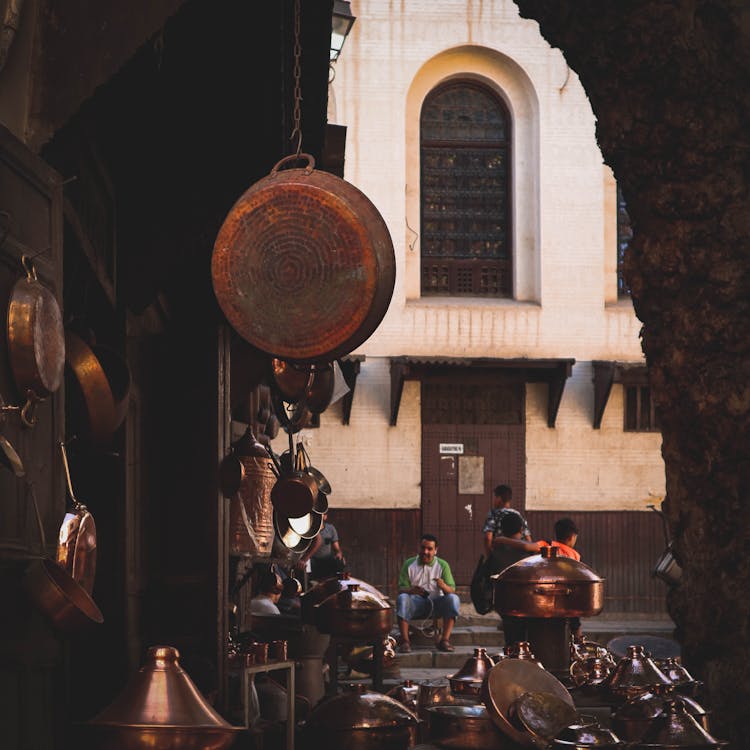 Brown Image Of A Traditional Market With Copper Pots And City Street In Background