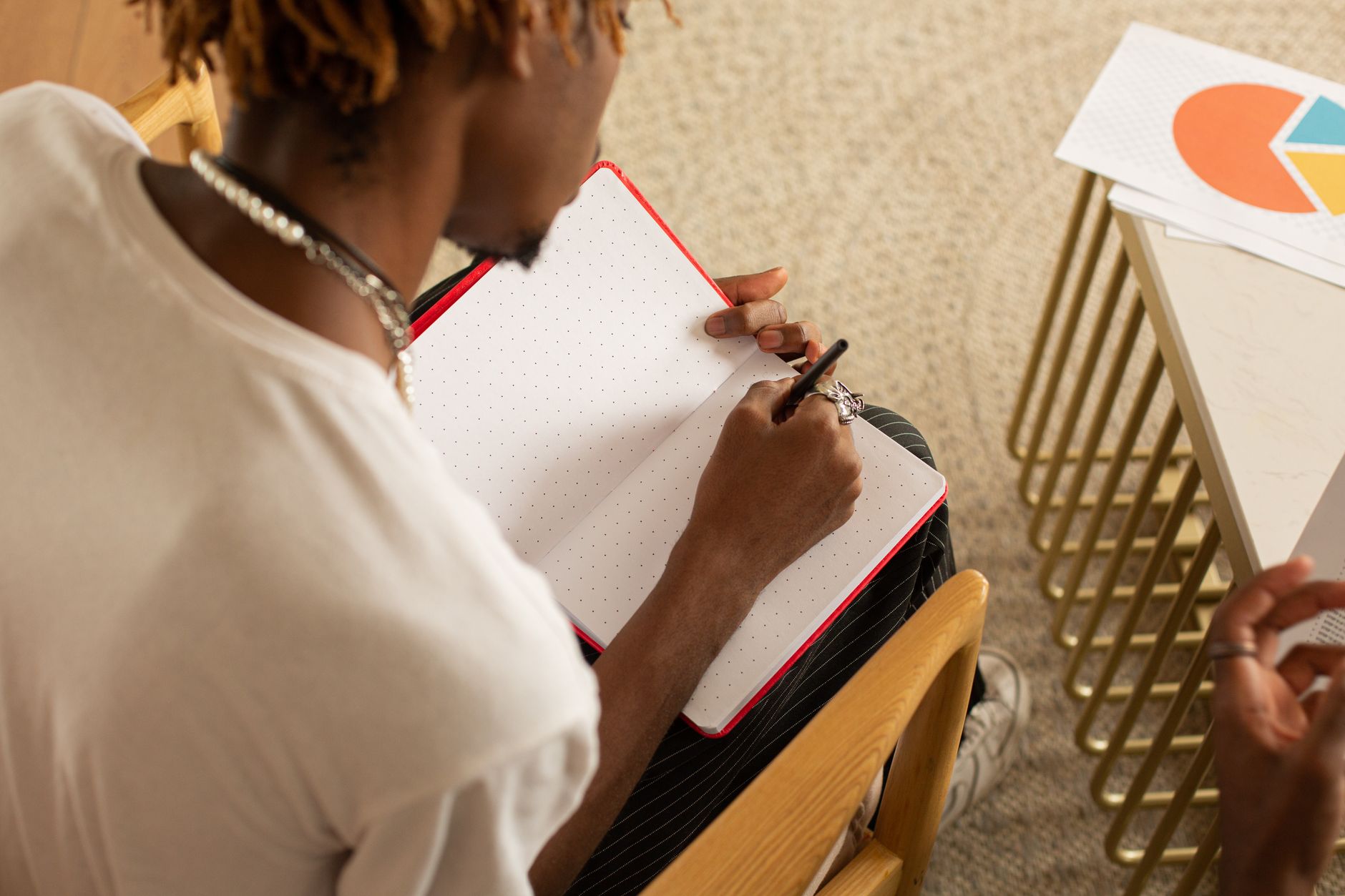 Man writing in a notebook at a table, featuring a chart. High angle view.