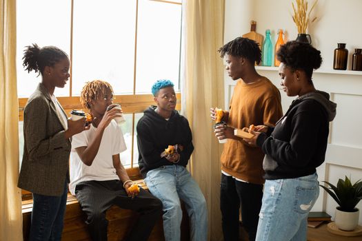 A diverse group of friends chatting and enjoying coffee indoors during the day.