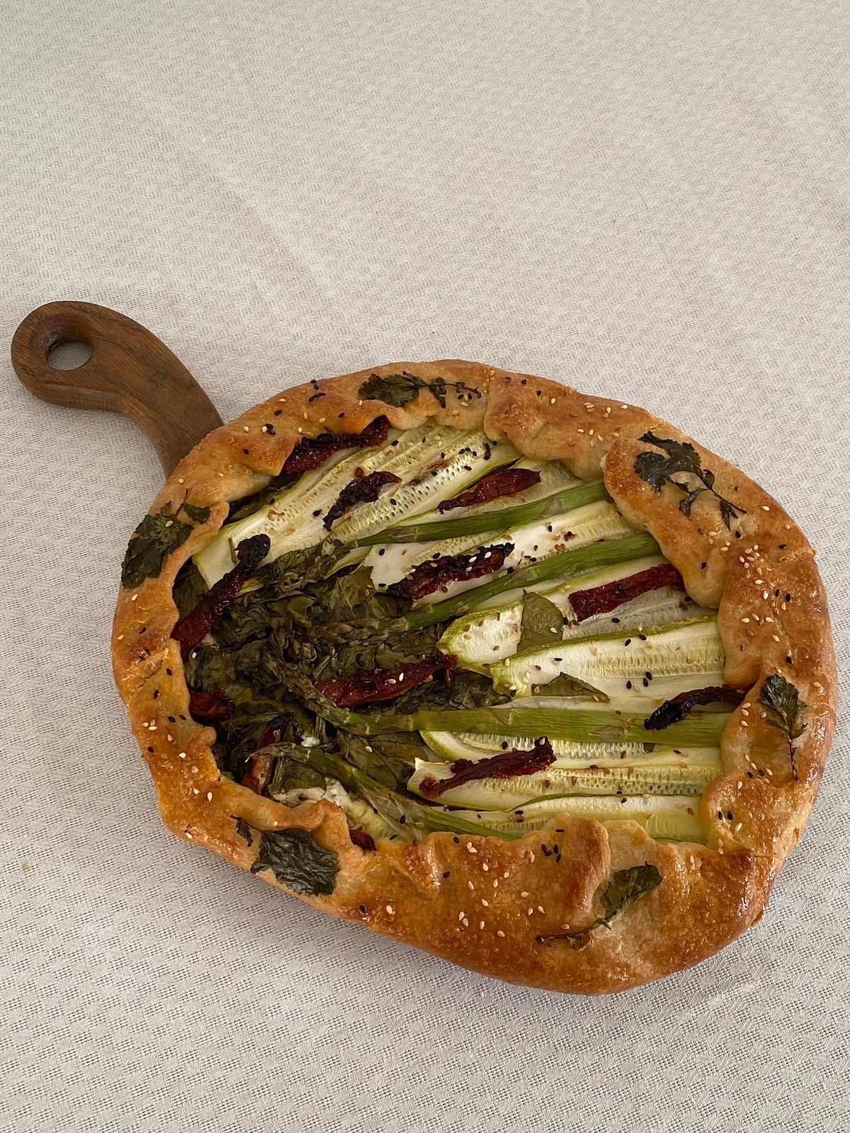 Homemade vegetable galette topped with zucchini and greens