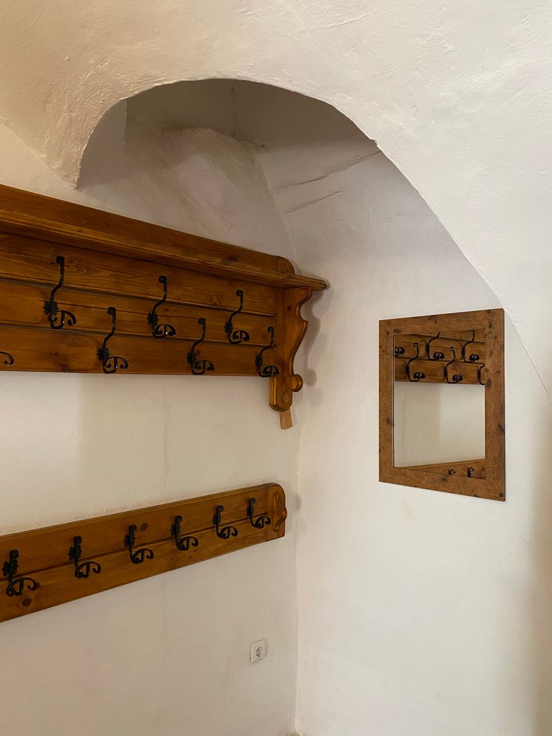 Wooden coat rack with black hooks mounted on a wall