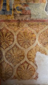 Detailed historic fresco featuring ornate floral patterns and warm yellow tones.