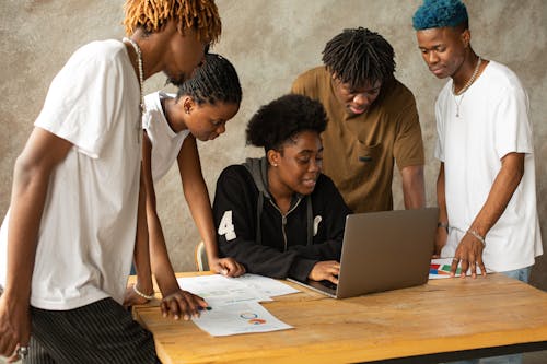 Woman surrounded by Men looking at Laptop 