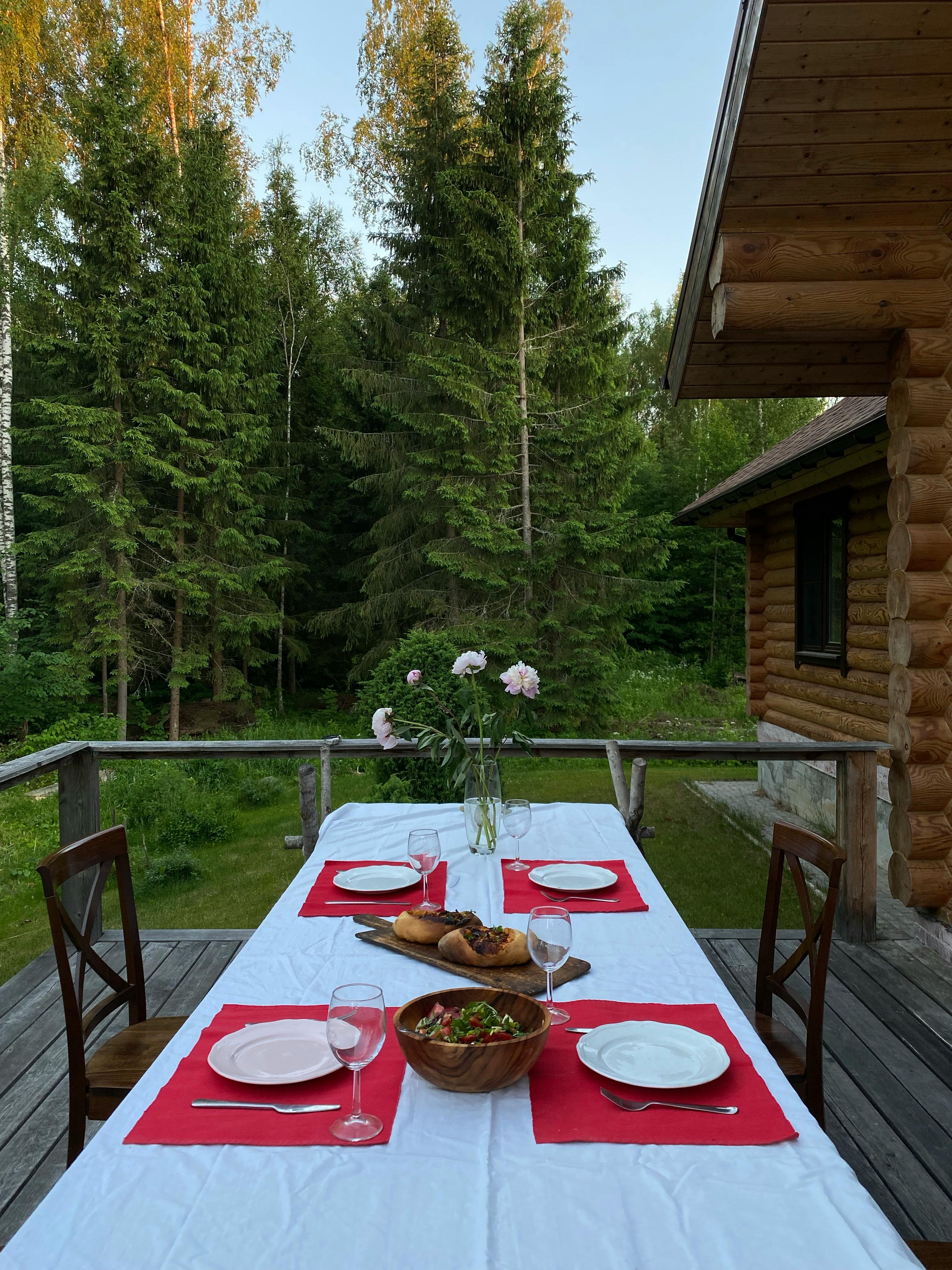 Elegant outdoor dining setup on a rustic cabin's terrace surrounded by forest.