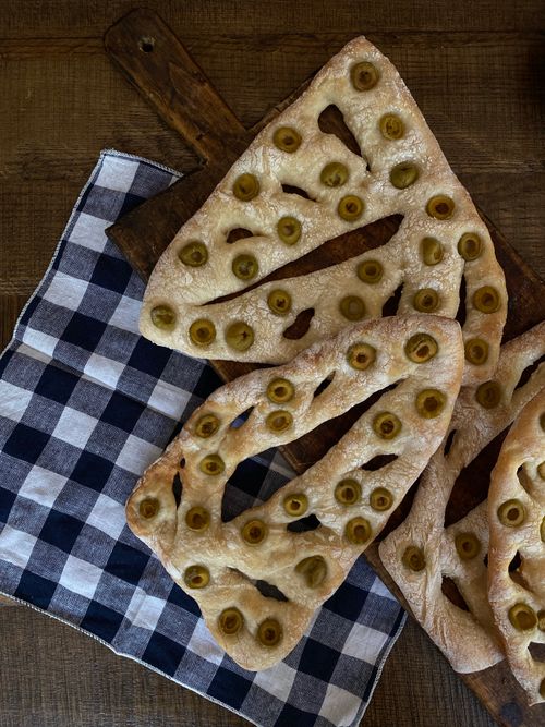 Free Top view of olive fougasse bread on checkered cloth, perfect for rustic food themes. Stock Photo