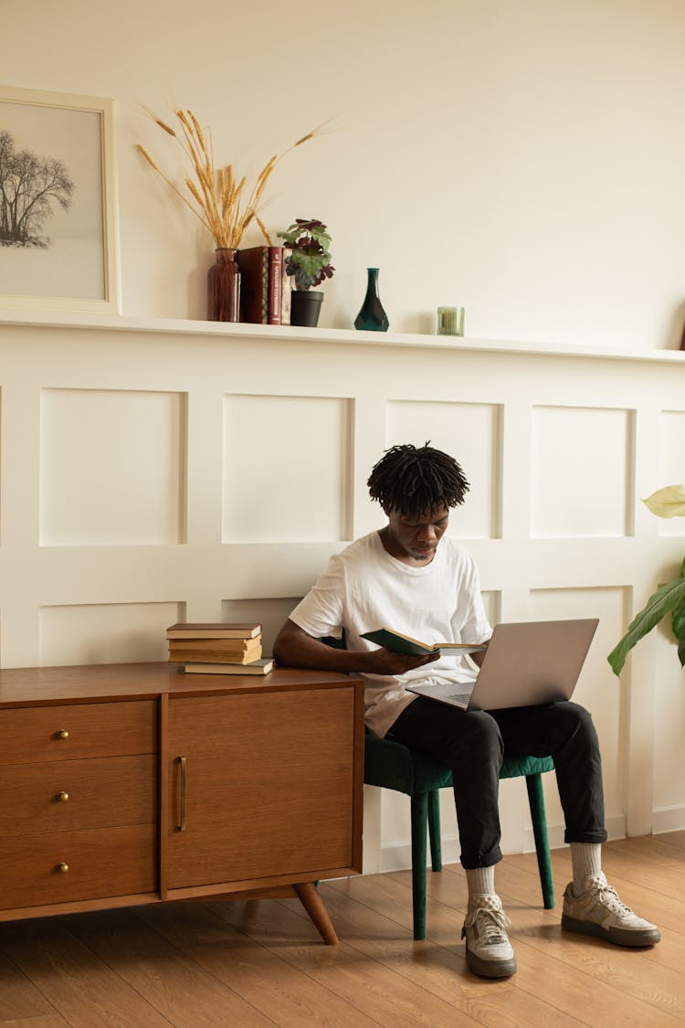 A Man Reading A Book While Sitting On A Chair