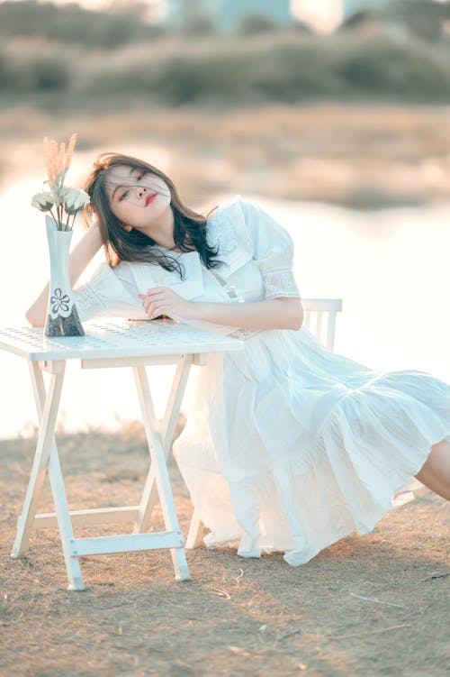 Free Woman in White Dress Sitting on White Wooden Chair Stock Photo