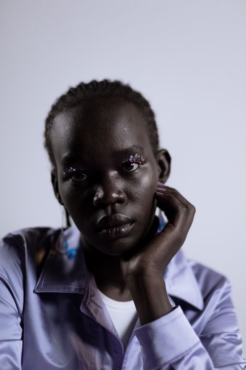 Free Close-up portrait of a thoughtful woman in a purple shirt with artistic makeup and elegant pose. Stock Photo