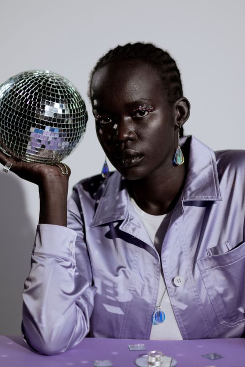 Free A striking portrait of a woman in glossy attire, holding a disco ball, exuding a modern and artistic vibe. Stock Photo