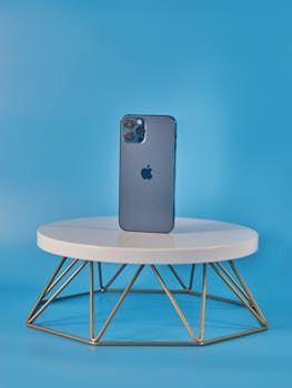 Stylish smartphone showcased on a geometric stand against a blue backdrop. Perfect for tech promotions.