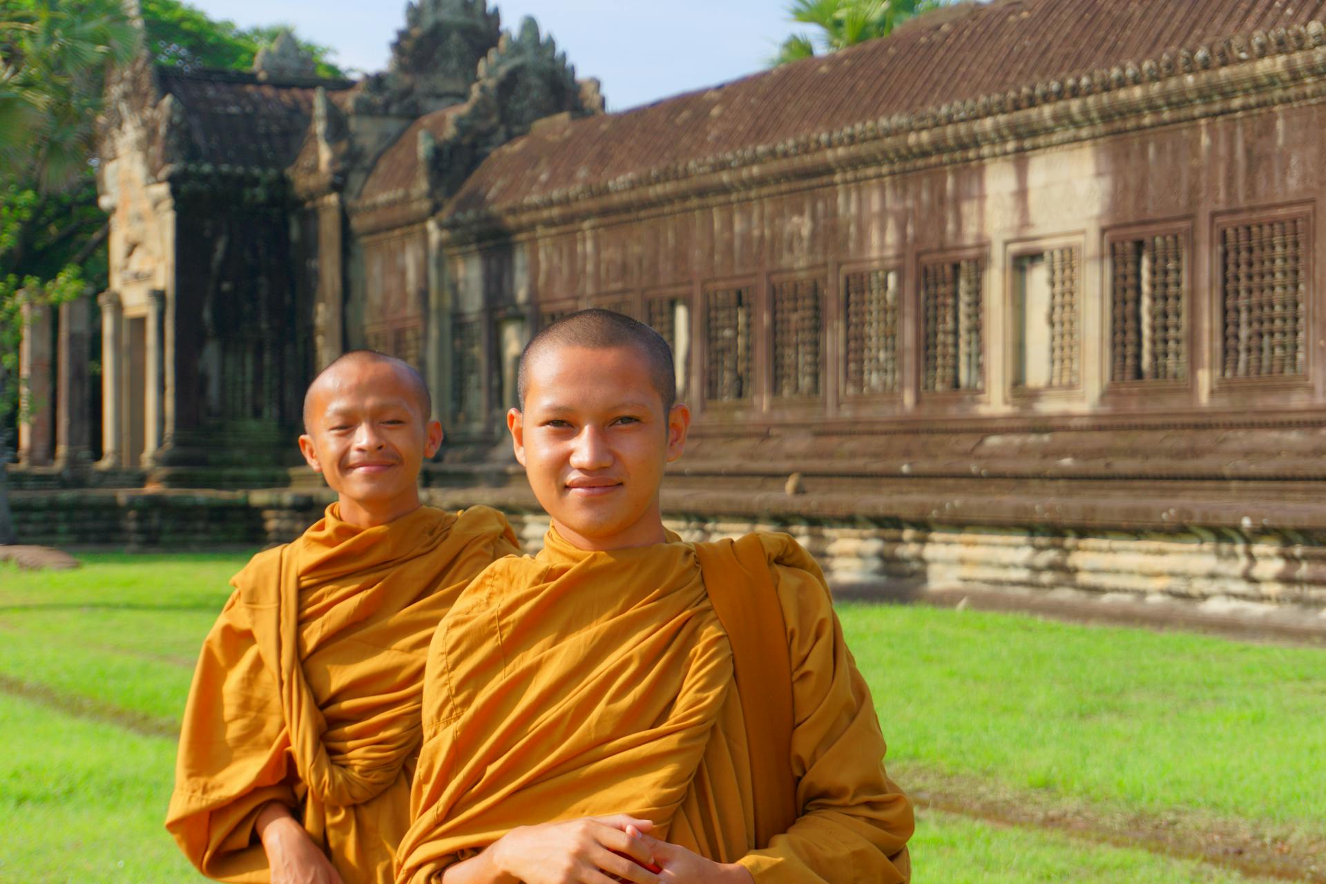 Two young monks in saffron robes at Angkor Wat, Cambodia during a sunny day.