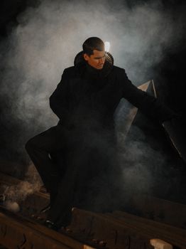 Dark and moody portrait of a man in elaborate costume with smoke around him.